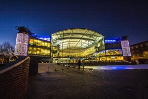 The Forum in Norwich lit up with yellow light at night 